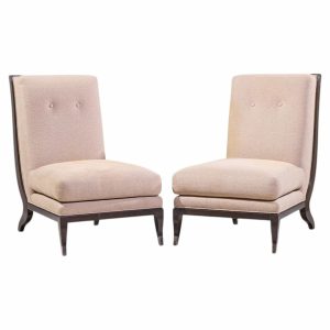 Pair of pale pink upholstered lounge chairs with dark wooden legs facing each other, mid-century style.