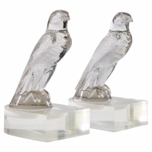 Two clear crystal bird figurines perched on square bases, shown side by side for display purposes.