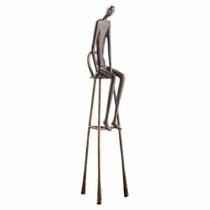 Tall rusted metal sculpture of a slender humanoid figure sitting on a tall minimalist chair/stool.