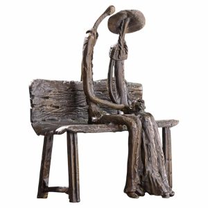 Bronze sculpture of a couple sitting closely on a bench, heads bowed toward each other.